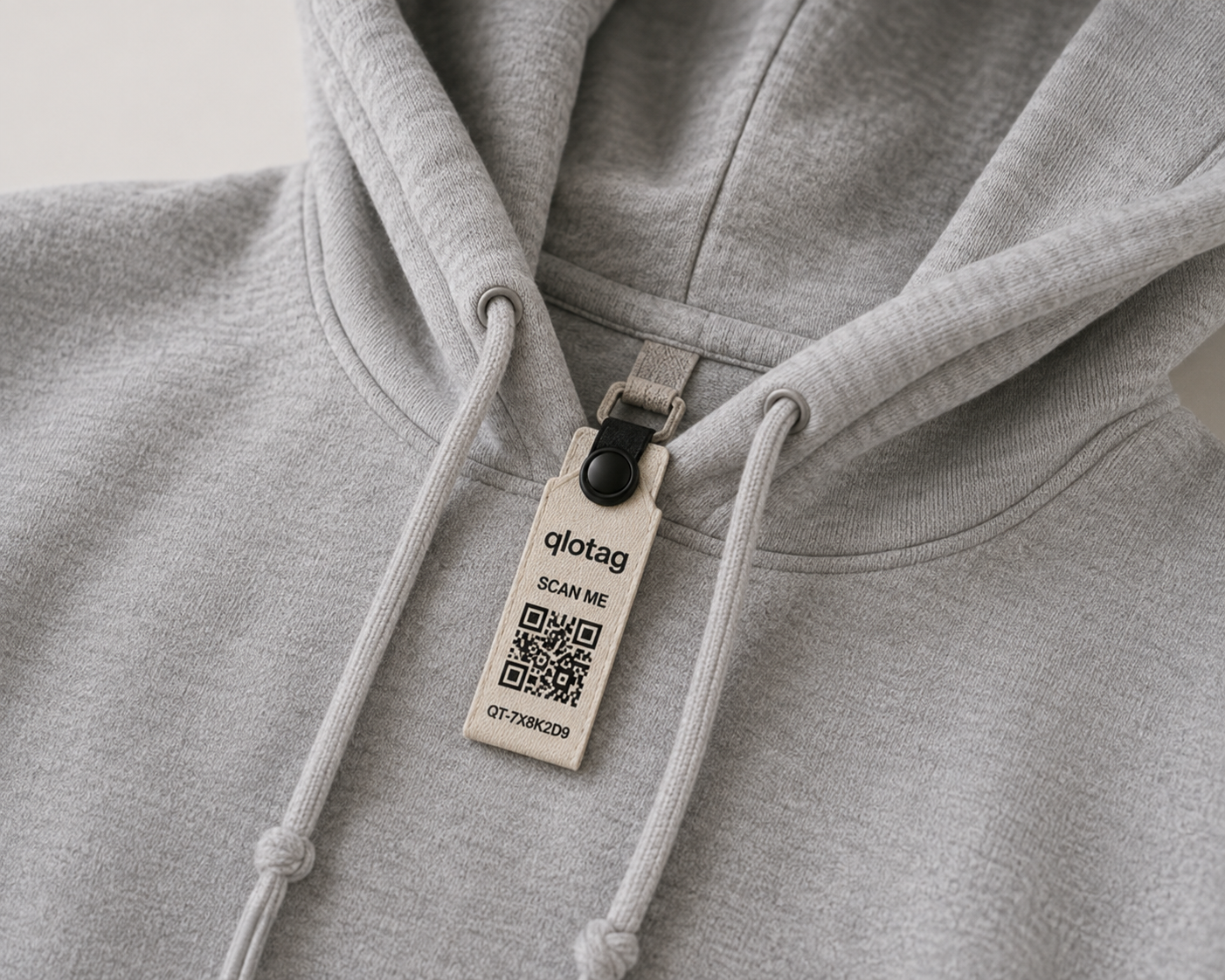 A qlotag tag attached to the drawstring loop of a grey hoodie